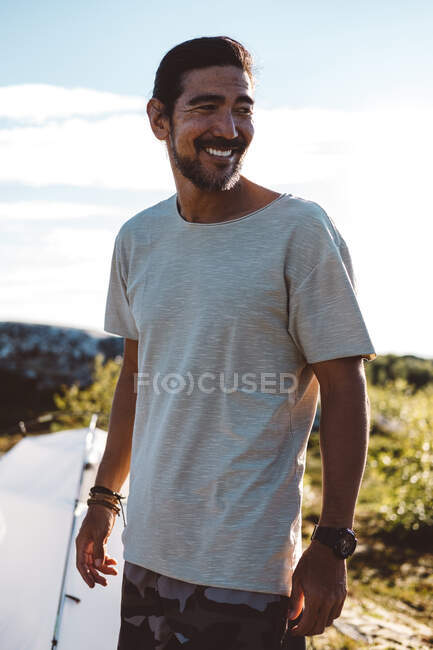 Homem olhando para longe sorrindo em um dia ensolarado em um acampamento — Fotografia de Stock