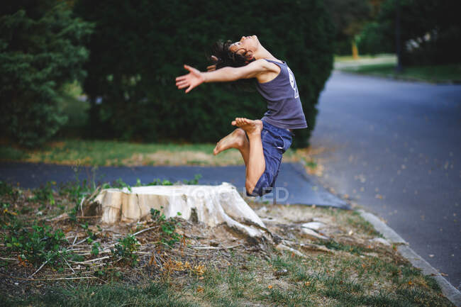 A graceful, athletic, barefoot boy leaps high in to the air in summer — Stock Photo