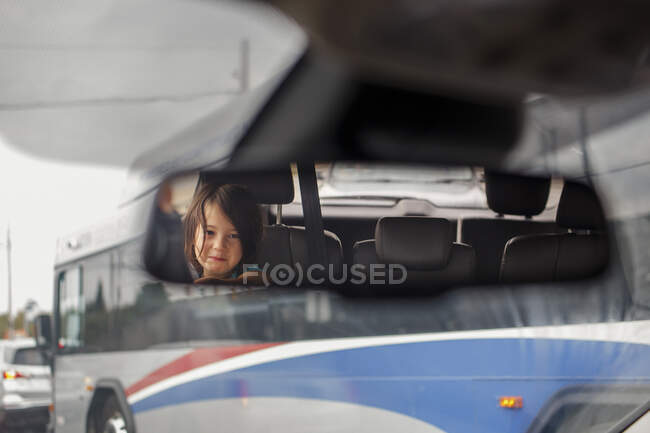 Милая маленькая девочка отражается в зеркале заднего вида автомобиля — стоковое фото