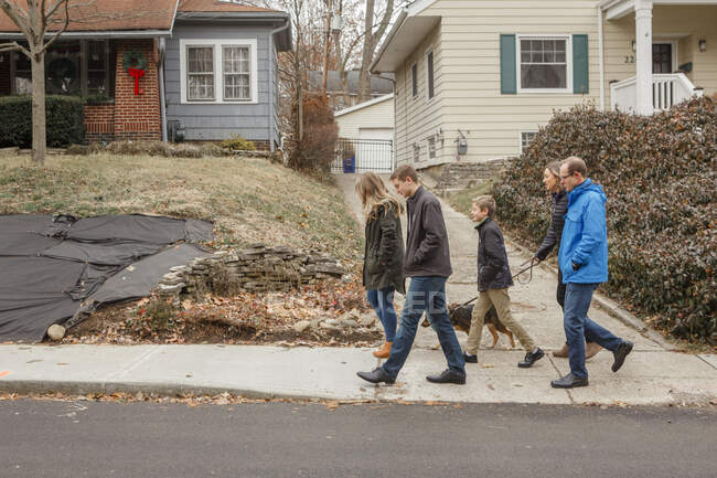Un paseo familiar junto con el perro por el barrio suburbano - foto de stock