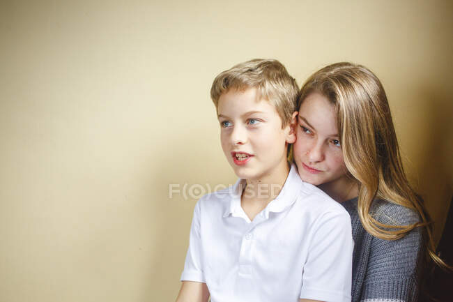 A young boy sits on his sisters lap smiling in soft window light — Stock Photo