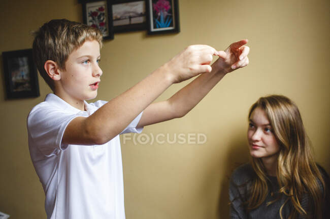 Um menino gesticula com as mãos enquanto conta a história para a irmã dentro — Fotografia de Stock