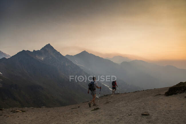Deux alpinistes montent un sentier au lever du soleil vers le sommet du Glacier Peak dans le Glacier Peak Wilderness à Washington. — Photo de stock