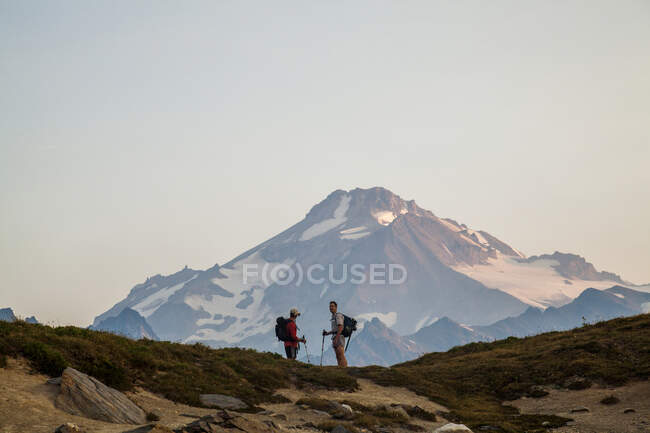 Two climbers ascend a trail at sunrise towards the Glacier Peak summit in the Glacier Peak Wilderness in Washington. — Stock Photo