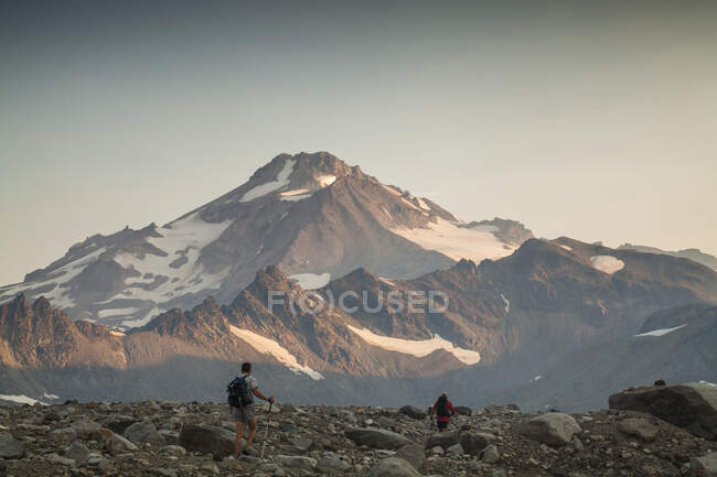 Two climbers ascend a trail at sunrise towards the Glacier Peak summit in the Glacier Peak Wilderness in Washington. (released: Sam Thompson and Brock Gavery) — Stock Photo