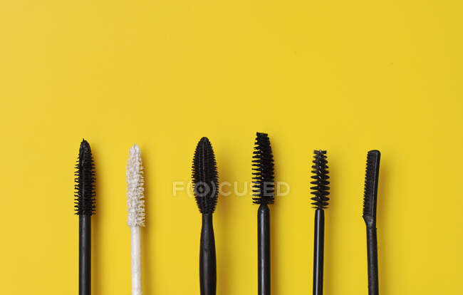 Various types of mascara wands on yellow surface — Stock Photo