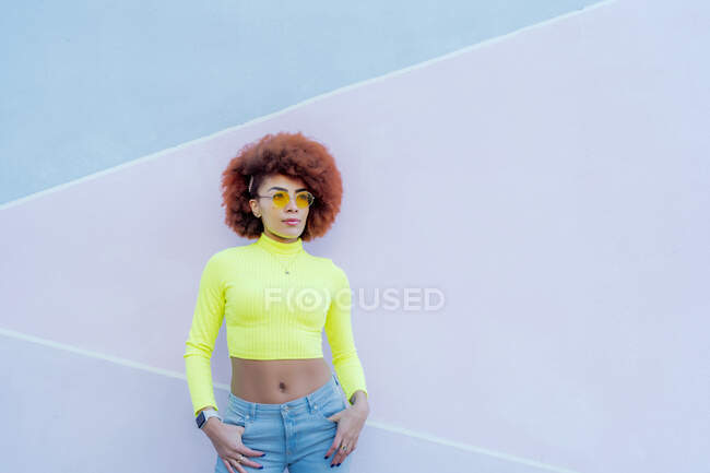 Portrait of gorgeous woman with afro hair over pink wall — Stock Photo