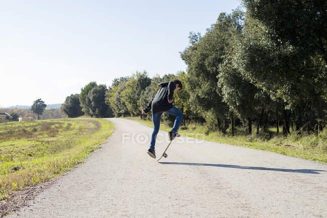 Action shot of a young skater teen male jumping high on a hill road — Stock Photo