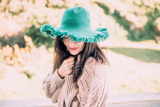 Темноволосая женщина в зеленой шляпе и очках наслаждается солнечным днем — стоковое фото