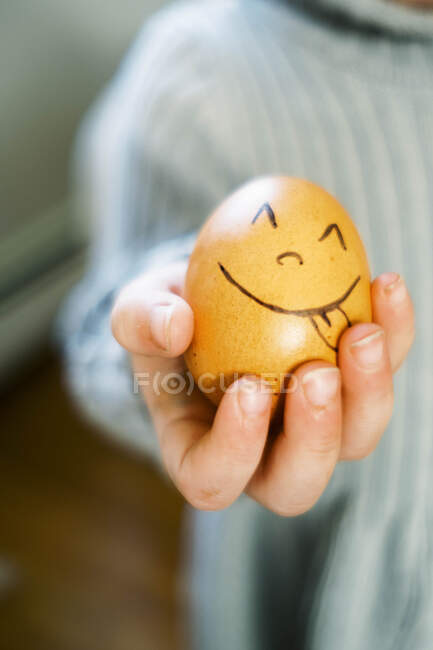 Toddler pretend playing with Easter eggs with silly cartoon faces — Stock Photo