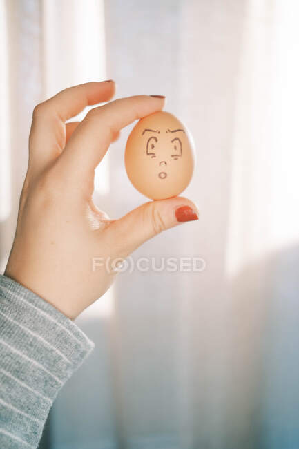 Woman holding an Easter egg with unique silly face art drawing — Stock Photo