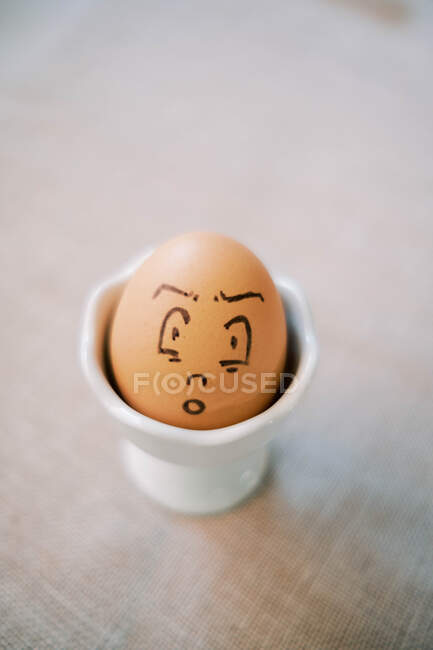 Funny cartoon art easter egg in porcelain dish with light background — Stock Photo