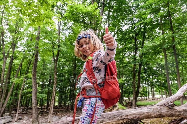 Portrait from downwards angle of girl giving thumbs up while hiking — Stock Photo