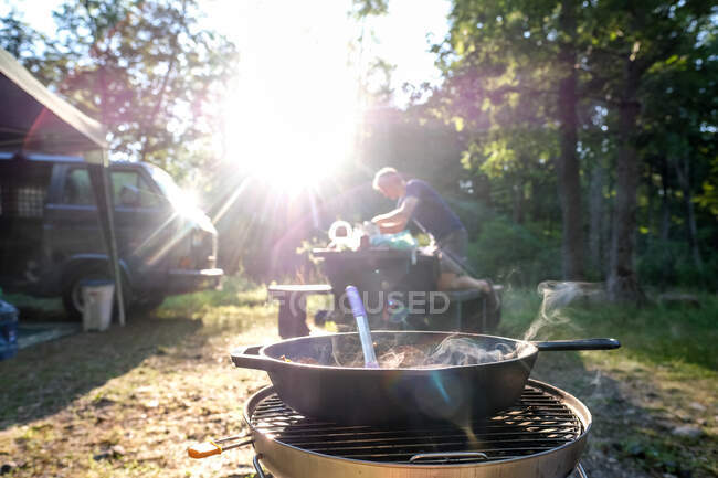 Man setting up dinner at campground food on stove — Stock Photo