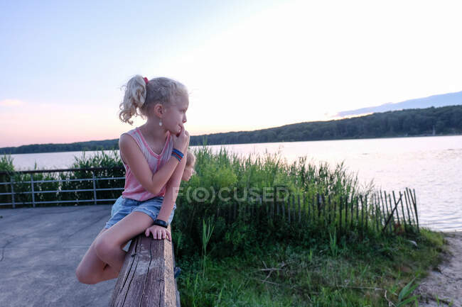 Dos chicas mirando hacia el lago al atardecer - foto de stock