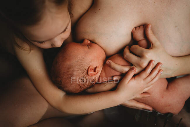 Top view of newborn baby breastfeeding and older sister hugging him — Stock Photo