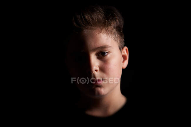 Fechar o rosto de uma criança grave parcialmente iluminada — Fotografia de Stock
