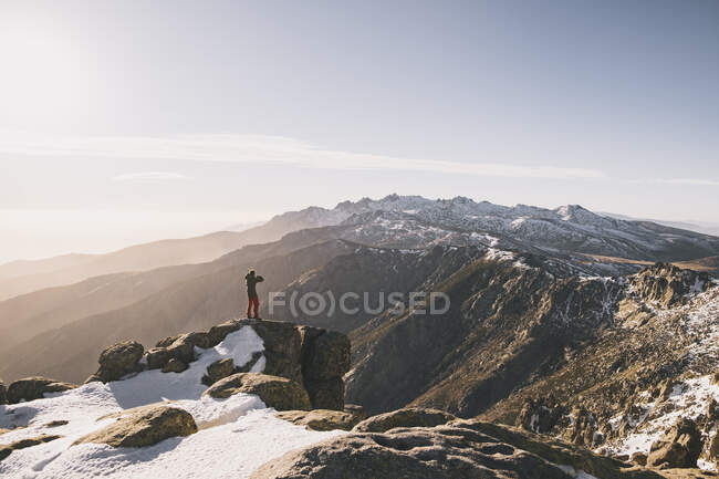 Junger Mann beim Fotografieren vor schneebedeckten Bergen bei Sonnenuntergang, Gredos, Spanien — Stockfoto