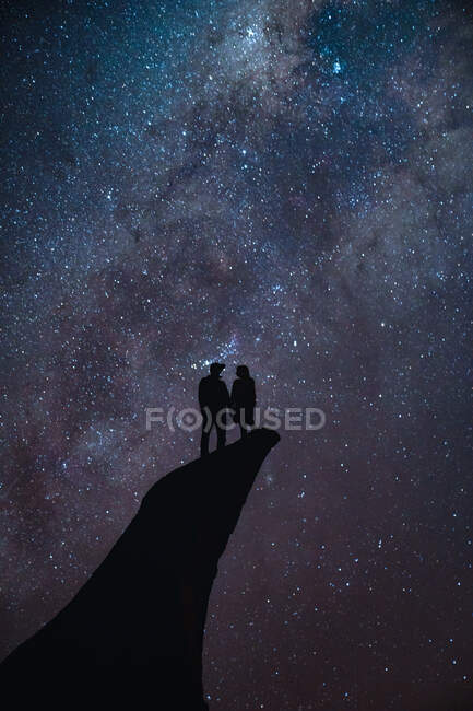 Couple standing on a cliff with the stars on the background — Stock Photo