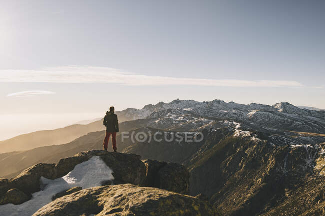 Junger Mann bewundert schroffe schneebedeckte Berglandschaft bei Sonnenuntergang, Gredos, Spanien — Stockfoto