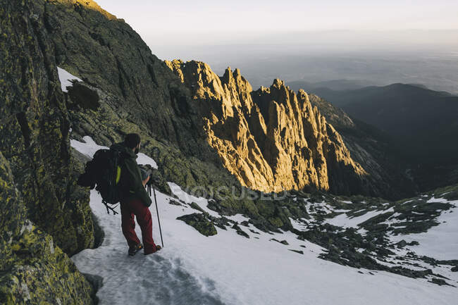 Young man assessing hike downhill situation during sunset at Gredos, Avila, Spain — Stock Photo