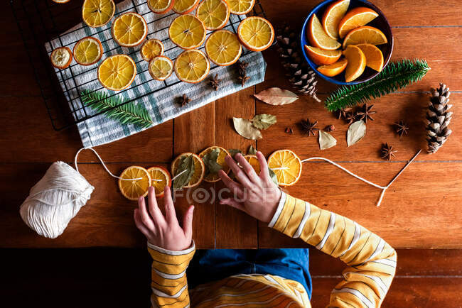 Childs manos juntando guirnalda de naranja seca para Navidad - foto de stock