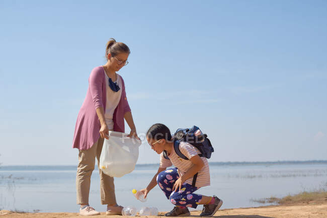 Figlia e madre hanno raccolto insieme bottiglie di plastica vicino al lago — Foto stock