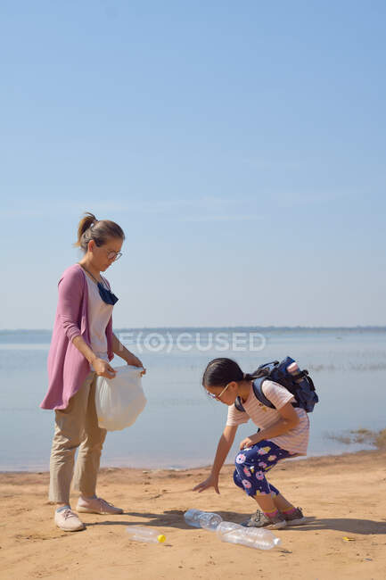 Дочь и мать собирали пластиковые бутылки у озера вместе — стоковое фото