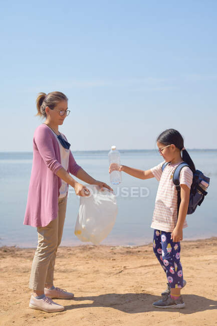 Дочь и мать собирали пластиковые бутылки у озера вместе — стоковое фото