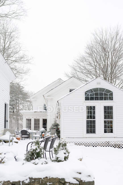 Casa branca com pátio na neve com luzes e árvore de Natal — Fotografia de Stock