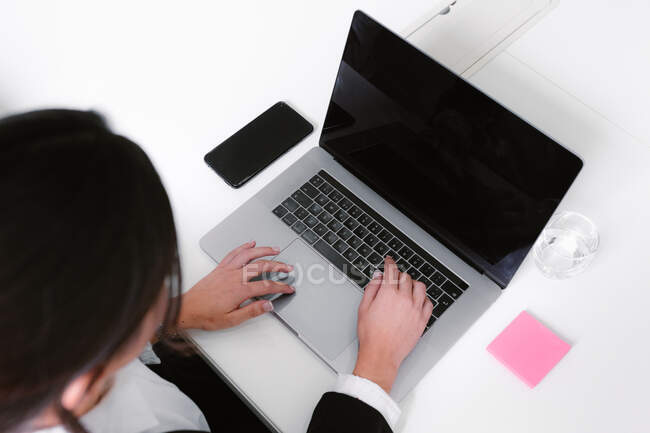 Joven mujer de negocios utilizando el ordenador portátil en el escritorio en la oficina - foto de stock