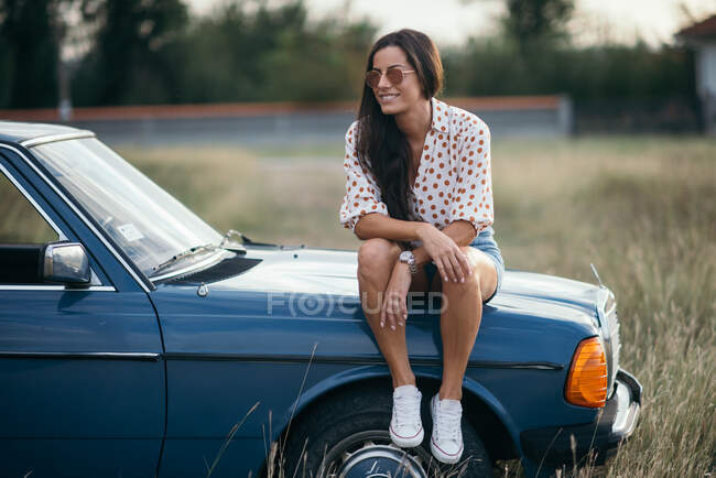 Lächelnde Frau sitzt auf dem Auto — Stockfoto