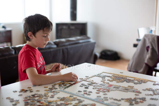 Junge setzt Puzzle am Küchentisch zusammen — Stockfoto