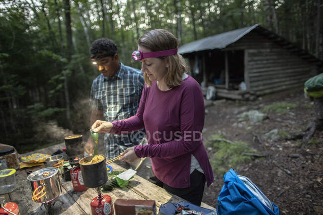 Casal com faróis cozinheiro na frente de Appalachian Trail abrigo Maine — Fotografia de Stock
