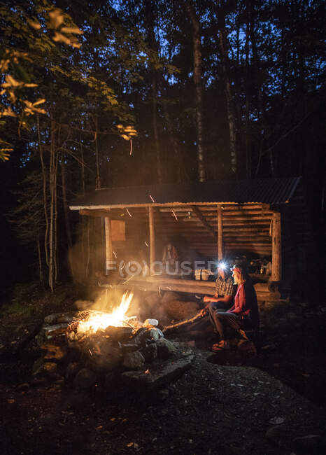 A couple sit by a campfire in front of shelter on Appalachian Trail — Stock Photo