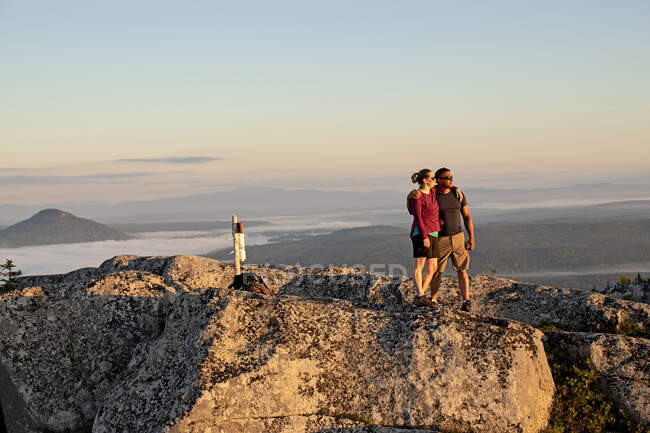 Pareja abrazos y abrazos después de llegar a la cima de la montaña en Maine - foto de stock