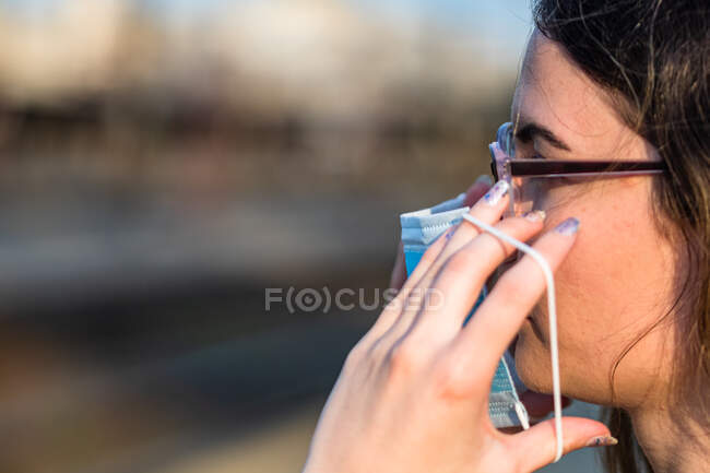 Женщина в медицинской защитной маске для лица иллюстрирует пандемическое коронавирусное заболевание на размытом фоне. Вспышка атипичной пневмонии в Европе. Осложнения, вызванные эпидемией — стоковое фото