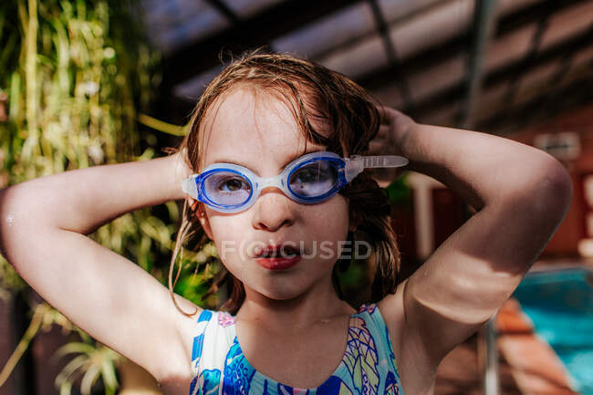 Chica joven que se pone gafas en una piscina - foto de stock