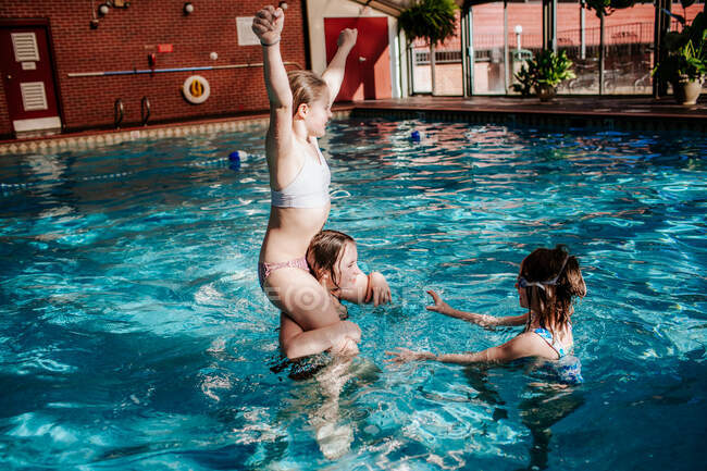 Trois filles jouant dans une piscine intérieure — Photo de stock