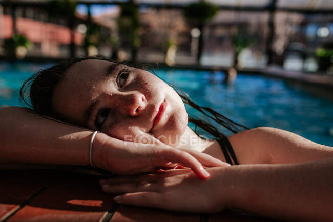 Glückliches Mädchen, das auf der Seite eines Swimmingpools ruht — Stockfoto