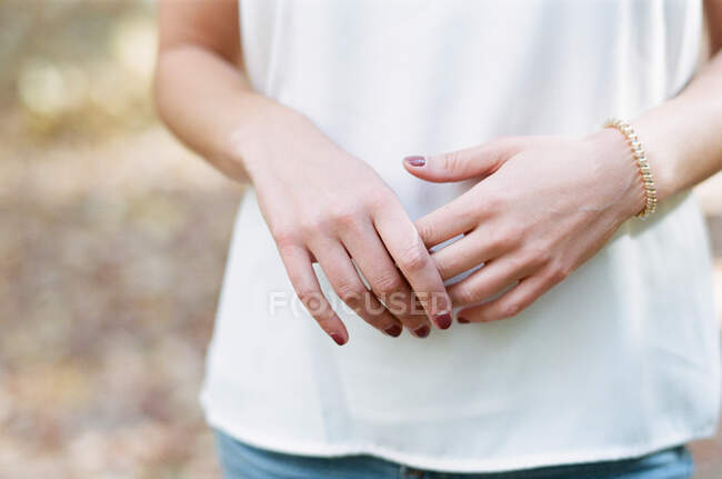 Woman holding hands in front of torso with bracelet simple background — Stock Photo