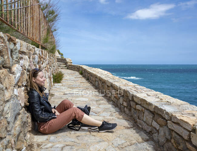 Fröhliches Mädchen in Rot genießt die Küste und blickt auf das Meer — Stockfoto