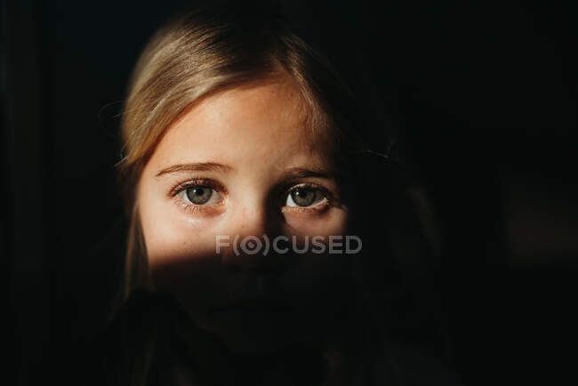 Little girl's eyes in bright light with black background — Stock Photo