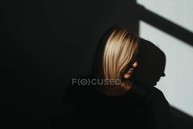Профиль женщины при ярком свете с черным фоном и тенями — стоковое фото