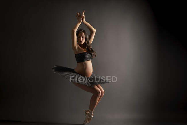 Молодая беременная балерина исполняет классическую балетную позу — стоковое фото