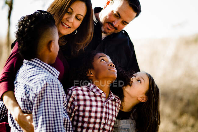 Семья из пяти человек обнимается и смотрит друг на друга — стоковое фото