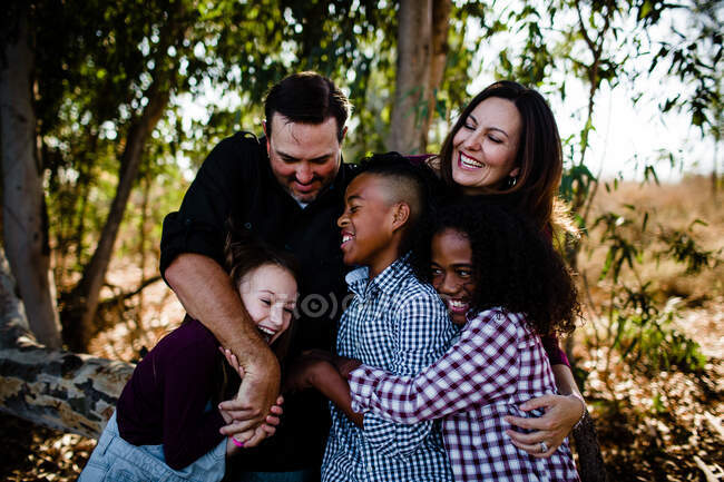 Familia de cinco abrazos y risas en el parque en Chula Vista - foto de stock