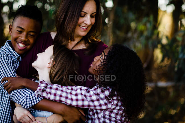 Mamá y niños abrazándose en mirarse el uno al otro - foto de stock
