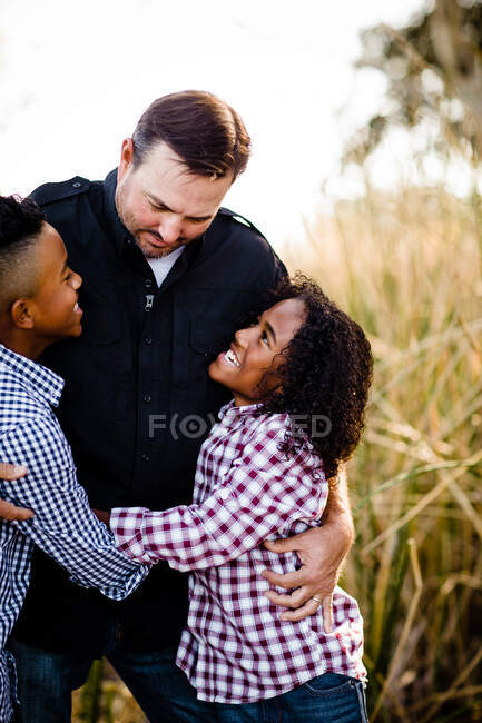 Padre e hijos abrazándose en el parque en Chula Vista - foto de stock