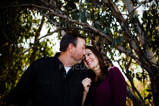 Marido y esposa posando bajo el árbol en el parque en Chula Vista - foto de stock